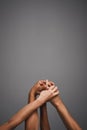 Getting a grip on diversity. Studio shot of unidentifiable hands holding on to each other against a gray background. Royalty Free Stock Photo