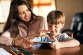 Getting hands on with homework. a little boy using a digital tablet while doing homework with help from his mother. Royalty Free Stock Photo