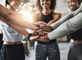 Getting a healthy dose of motivation. a group of young people joining their hands together in solidarity at a gym.