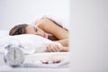 Getting her 8 hours. A woman sleeping in her bed with an alarm clock in the foreground. Royalty Free Stock Photo