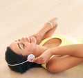 Getting lost in the music. a young woman listening to music while lying on a wooden floor. Royalty Free Stock Photo