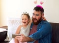 Getting a makeover means its selfie time. an adorable little girl playing dress up and taking selfies with her father at Royalty Free Stock Photo