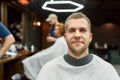 Getting new haircut. Portrait of young handsome bearded man sitting in barbershop chair and smiling at camera. Visiting Royalty Free Stock Photo