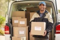 Getting packages on their way. Portrait of a smiling delivery man standing in front of his van holding a package. Royalty Free Stock Photo