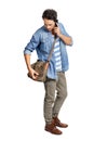 Getting ready for college. A handsome young man looking for something in his sling bag while talking on his phone. Royalty Free Stock Photo