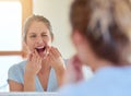 Getting rid of all her plaque. a young woman flossing her teeth in a mirror. Royalty Free Stock Photo