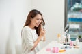 Getting rid of tangles. Beautiful young woman looking at her reflection in mirrorand brushing her long hair while sitting at the