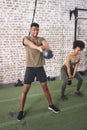 Getting into shape is a lot harder than it looks. two sporty young people using kettlebells while working out at the gym Royalty Free Stock Photo
