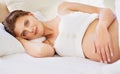 Getting some rest now for the sleepless nights ahead. A beautiful young pregnant woman lying on her bed and looking at Royalty Free Stock Photo