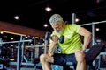 Getting strong arms. Focused mature man in sportswear lifting heavy dumbbells and pumping his biceps while working out