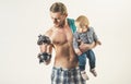 Getting stronger. Active family enjoy sport and fitness. Strong man with dumbbells hold baby boy. Father build biceps