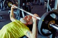 Getting stronger. Strong mature caucasian man lifting weighted bar or barbell at gym