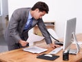 Getting swamped at work. A handsome businessman multitasking at his desk. Royalty Free Stock Photo