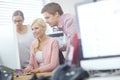 Getting their opinions. three young coworkers gathered around a single computer.