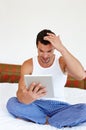 Getting to grips with new technology. A man sitting on his bed holding a digital tablet. Royalty Free Stock Photo