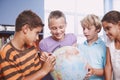 Getting to know the different countries of the world. A group of schoolkids learning about the world using a globe of