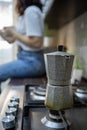 geyser coffee kettle on the cook top at the kitchen woman drinking on background