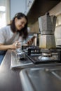 geyser coffee kettle on the cook top at the kitchen woman drinking on background