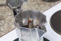 A geyser coffee machine is on the electric stove. It is visible as ready coffee under pressure pours out in the container.