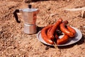 Geyser coffeemaker. Meat sausages are fried on a steel grilled grill against the backdrop of coals Royalty Free Stock Photo