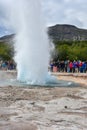 Strokkur geyser erupting and many tourists waiting