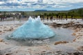 Strokkur geyser erupting and many tourists waiting