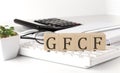 GFCF written on a wooden cube on keyboard with office tools