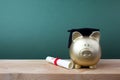 Gfold piggy bank with a grad cap and diploma in front of green chalkboard. Education scholarship Royalty Free Stock Photo