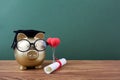 Gold piggy bank with a grad cap and diploma in front of green chalkboard. Education scholarship Royalty Free Stock Photo