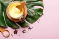 Ghee butter in a glass jar, pink salt and spices on pink background