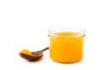 Ghee or clarified butter in jar and wooden spoon isolated