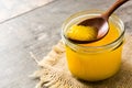 Ghee or clarified butter in jar and wooden spoon on woode. Copyspace