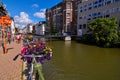 Ghent, Belgium, August 2019. Planters with brightly colored plants and some parked bikes stand out along the canals. People walk