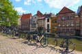 Row medieval colored buildings along Lys River dutch: Leie. Embankment with parked bicycles along the fence.