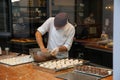 View through display window in belgian bakery with male baker preparing fresh dough