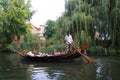 View on water canal with old chinese boat, people meditating and a man with paddle