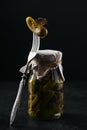 Gherkins, pickled cucumber on a fork, glass jar with marinated vegetables on a black background Royalty Free Stock Photo