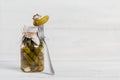 Gherkins, pickled cucumber on a fork, marinated vegetables in a glass jar on white wooden background Royalty Free Stock Photo