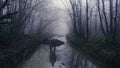 A ghost figure reflected in a pond in an eerie forest. On a mysterious foggy, winters day