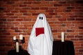 Ghost holding book over brick background. Halloween party. Royalty Free Stock Photo