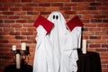 Ghost holding books over brick background. Halloween party. Royalty Free Stock Photo