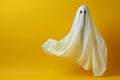 Ghostly apparition white sheet aloft against minimal yellow Halloween backdrop