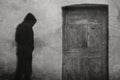 A ghostly spooky hooded monk. Standing by an old wooden door. With a grunge, vintage black and white edit Royalty Free Stock Photo