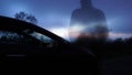 A ghostly transparent man with back to the camera, standing by a car looking out a sunset On a winters evening. With a burred,