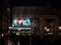 Giant advertising sign at night on the facade of a building in t