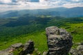 Giant boulder on a cliff over the grassy hillside