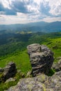 Giant boulder on a cliff over the grassy hillside