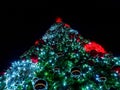 A giant Christmas tree decorated with many balls and garlands glows in the night. Bottom up view Royalty Free Stock Photo