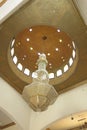 A giant crystal chandelier suspended under an arched ceiling. Luxury entrance hall lighting. Decorated chandelier hangs in the