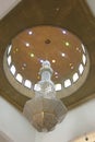 A giant crystal chandelier suspended under an arched ceiling. Luxury entrance hall lighting. Decorated chandelier hangs in the Royalty Free Stock Photo